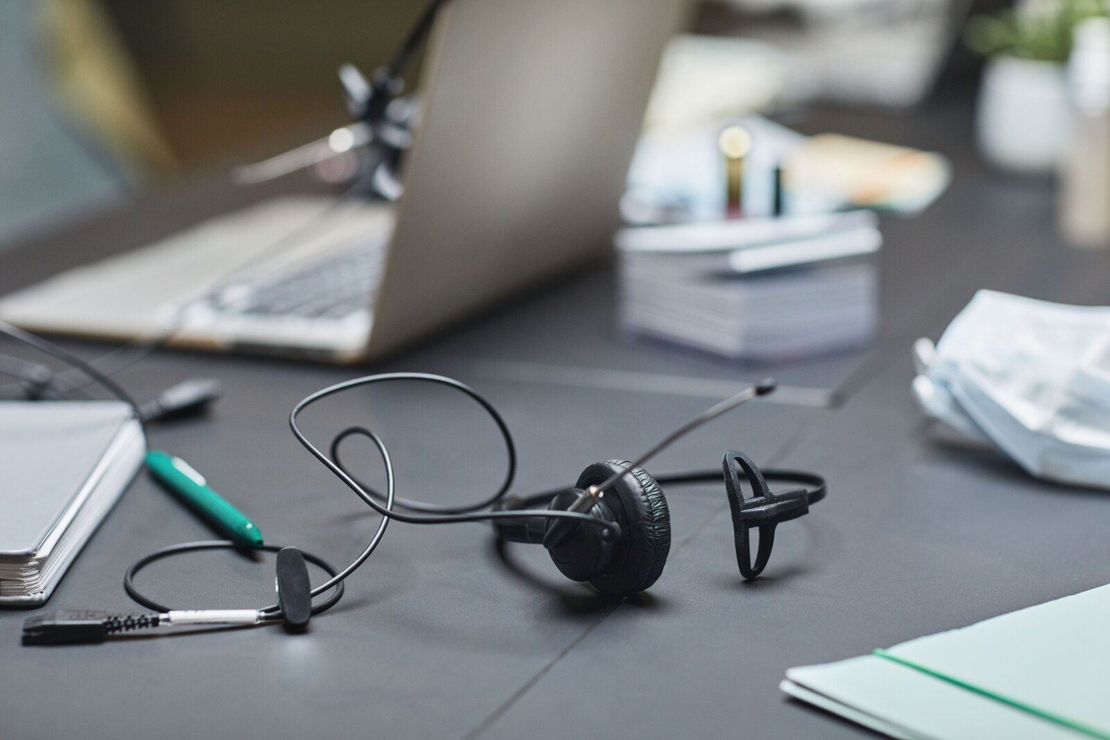 Headset mit Mikrofon auf einem Schreibtisch neben einem aufgeklappten Laptop