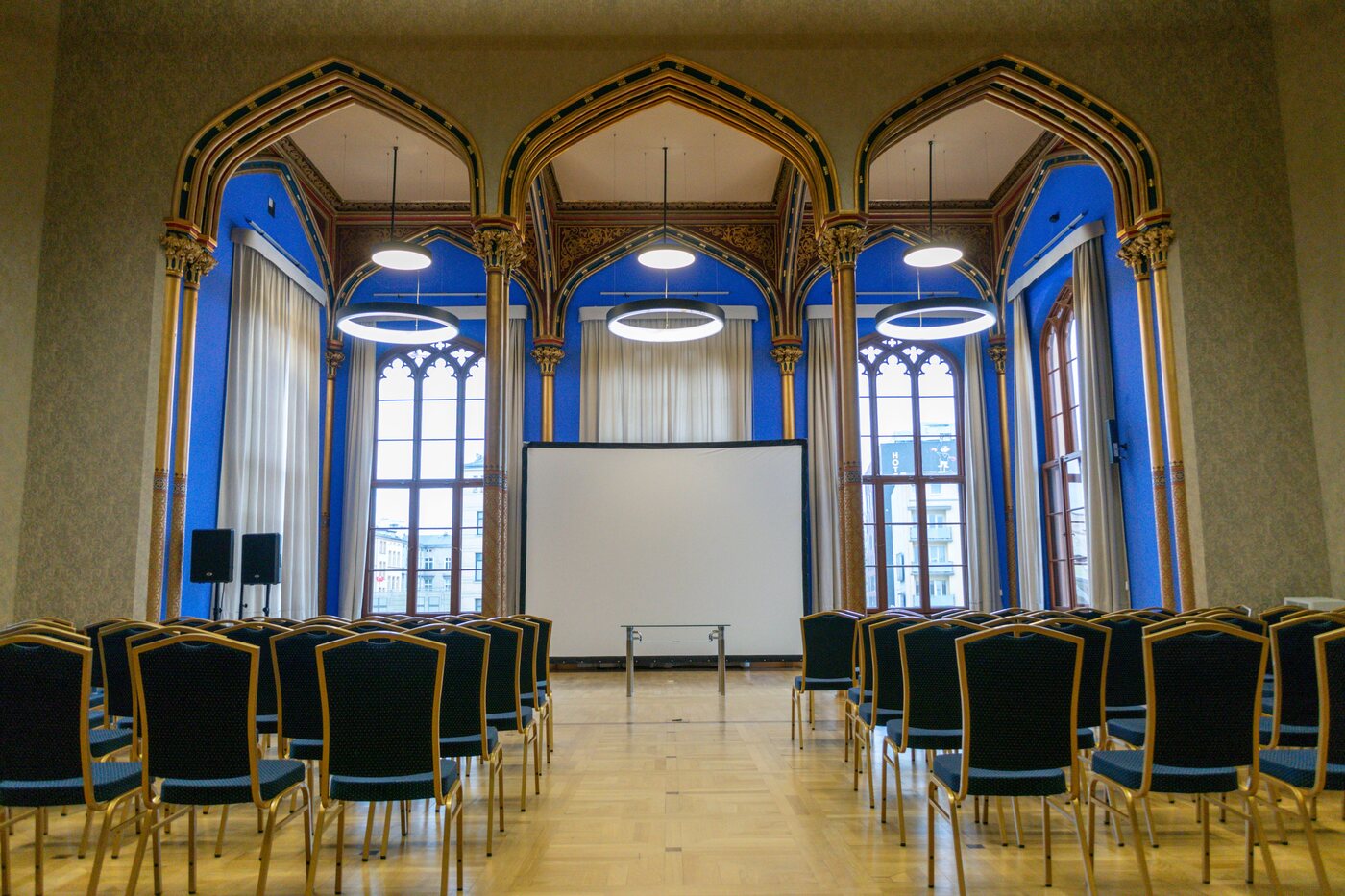 Historischer Saal mit Spitzbögen und verzierter Decke, bestuhlt und mit Projektionsleinwand für eine Veranstaltung