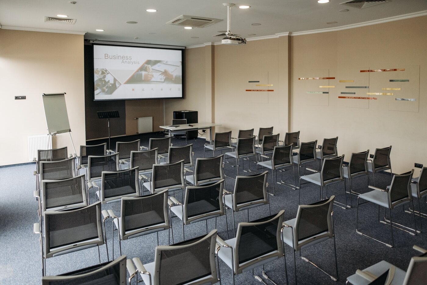 Seminarraum mit Stuhlreihen, Projektionsleinwand und Flipchart
