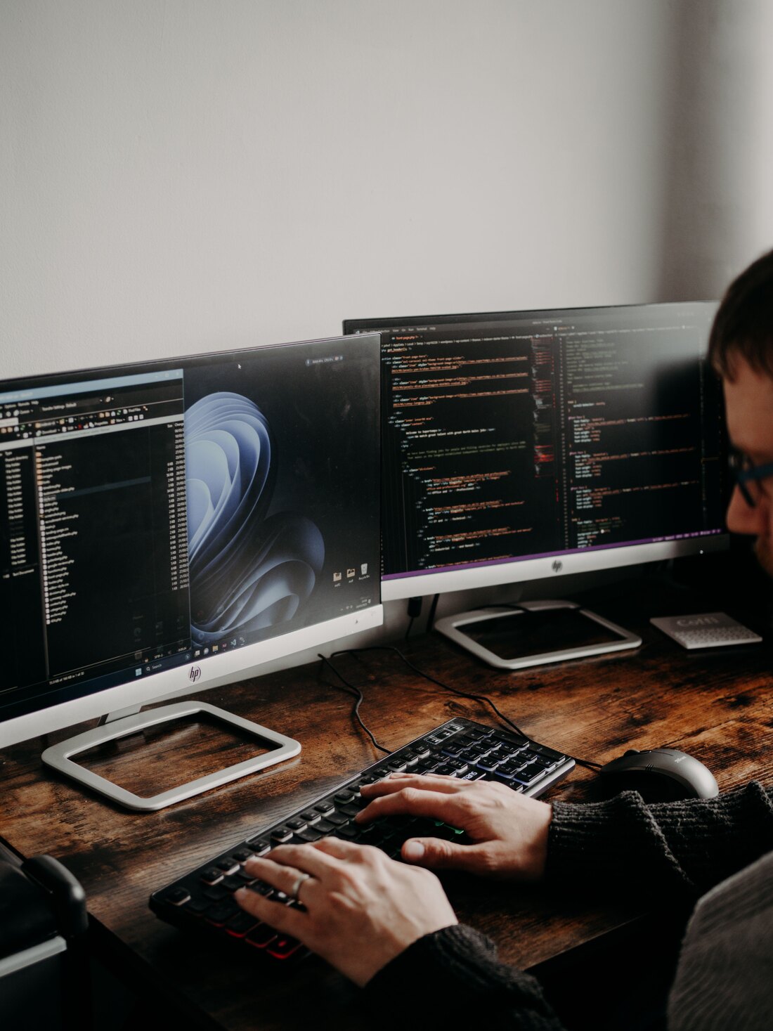 Entwicklerarbeitsplatz mit zwei Bildschirmen, auf einem ist Programmcode geöffnet